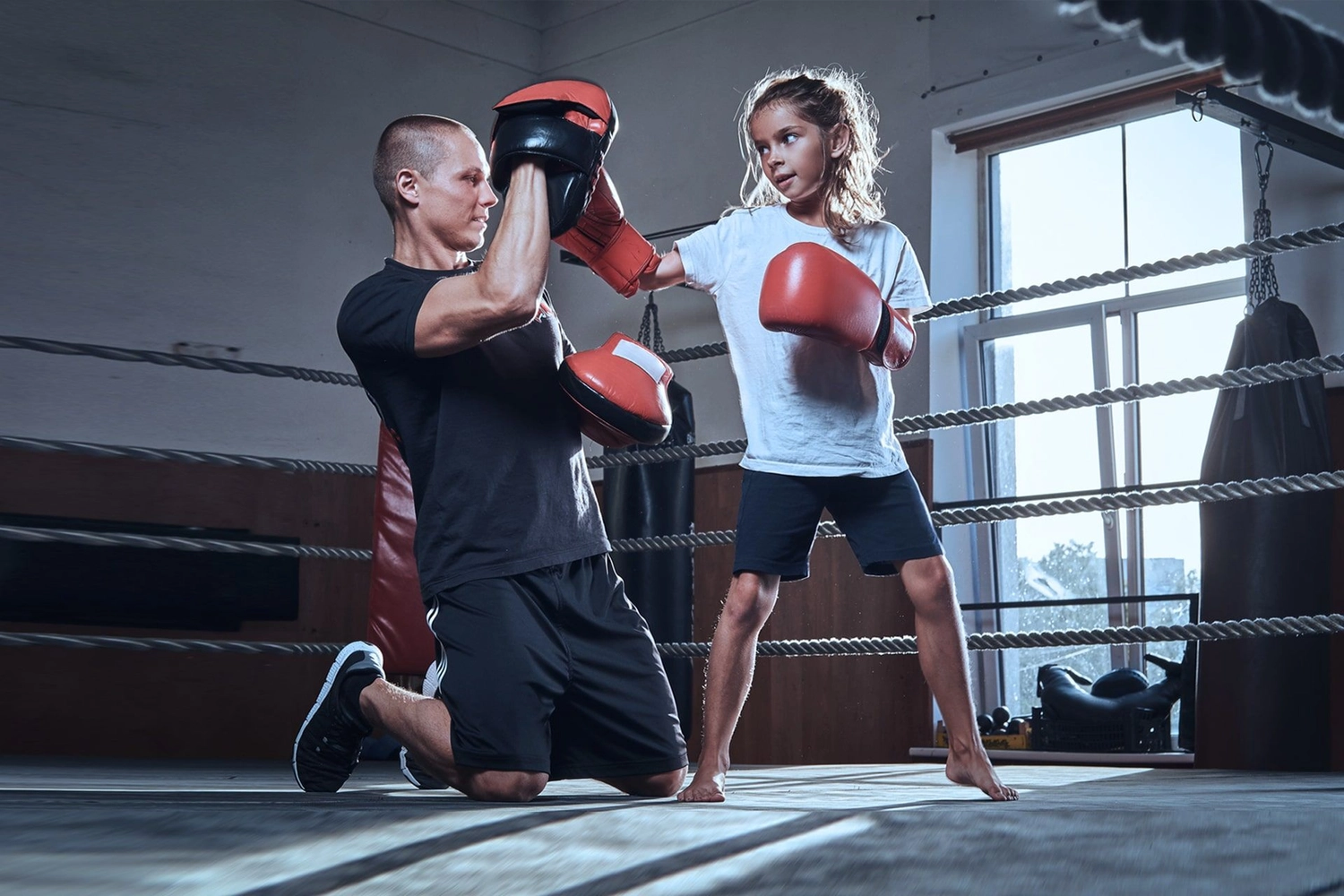 Atrium Sports e.V. - Kampfsport und Fitness - ein junges Mädchen trainiert mit einem Trainer in einem Boxring.