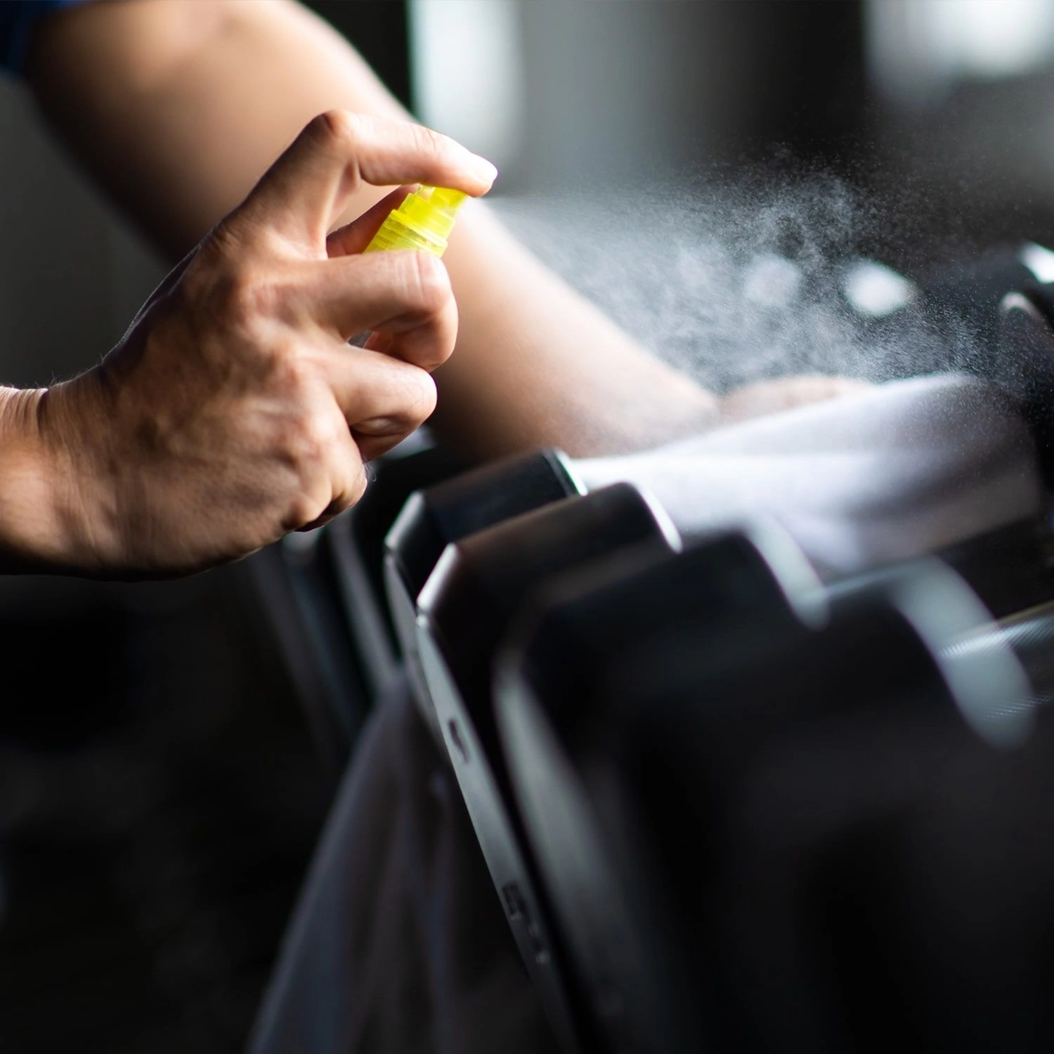 Atrium Sports e.V. - Kampfsport und Fitness – eine Person, die Hanteln mit einer Reinigungs- oder Desinfektionslösung besprüht